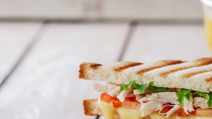 sándwich de pollo con queso y un vaso de jugo de naranja