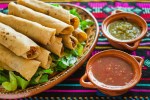 Un plato con flautas de carnitas, salsas clásicas y lechuga
