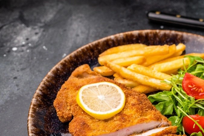 Milanesa de pollo empanizada con ensalada de berro y tomate
