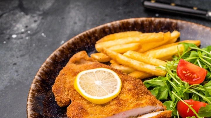 Milanesa de pollo empanizada con ensalada de berro y tomate