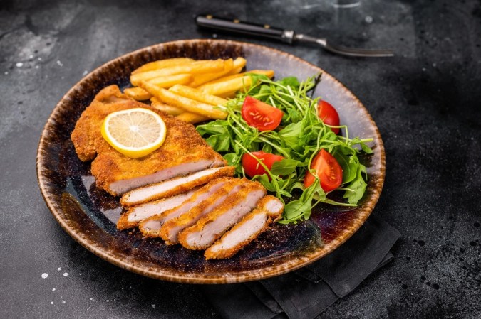Milanesa de pollo empanizada con ensalada de berro y tomate