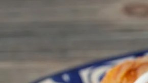 Un plato de color azul con burritos mexicanos, salsa y tomate