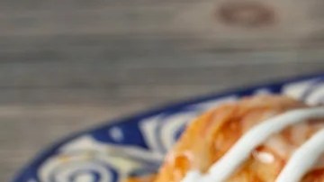 Un plato de color azul con burritos mexicanos, salsa y tomate