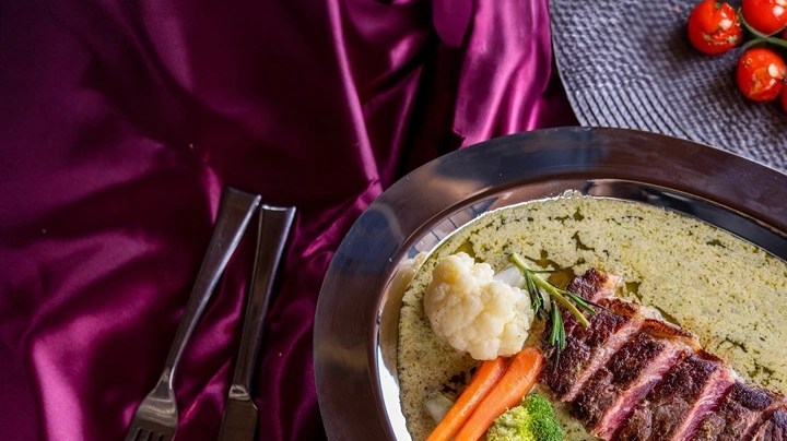 Entrecot de ternera estilo París sobre una bandeja de aluminio y una mesa decorada