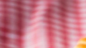 Galletas reinitas de mermelada de fresa sobre un mantel de cuadros rojos y una taza blanca