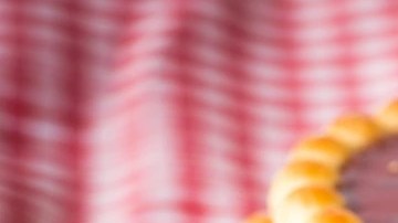 Galletas reinitas de mermelada de fresa sobre un mantel de cuadros rojos y una taza blanca
