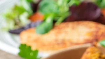 Mesa con mantel marrón con diferentes platos con hamburguesas de carne vegana y papas fritas