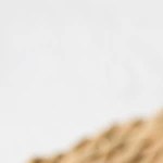 Plato blanco hondo con rigatoni con berenjena y mozzarella sobre una mesa marrón