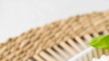 Plato blanco hondo con rigatoni con berenjena y mozzarella sobre una mesa marrón