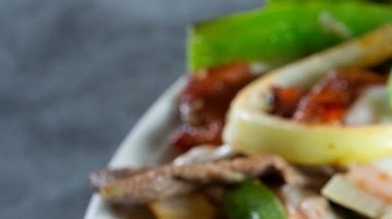 Plato blanco con alambre mexicano y aguacate sobre una mesa gris