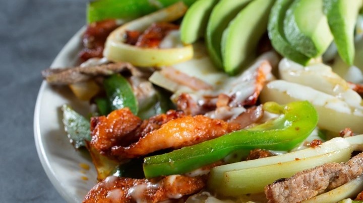 Plato blanco con alambre mexicano y aguacate sobre una mesa gris