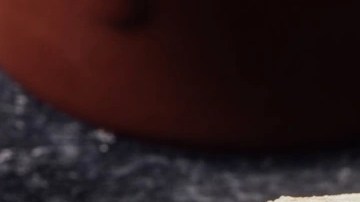 Una arepa rellena de carne mechada o desmechada sobre una mesa de color negro