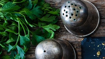 Berenjenas rellenas de carne, queso y verduras sobre un plato de aluminio, decorada con verduras