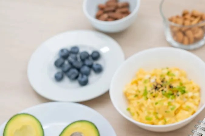 Persona anotando en su libreta el menú semanal junto a platos de frutos y verduras