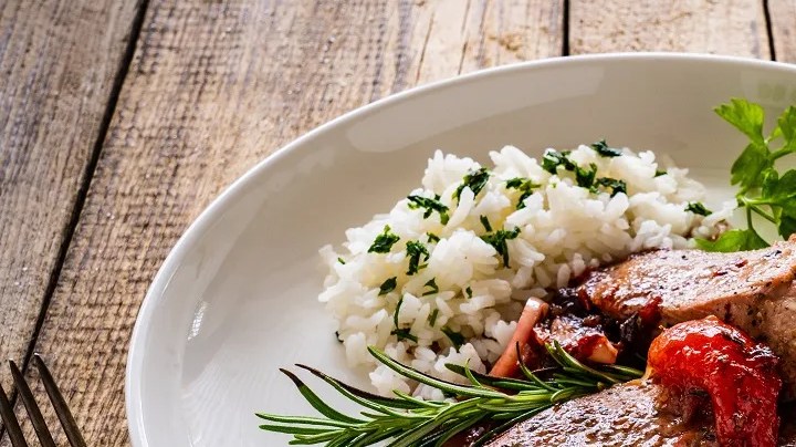 Un plato blanco con cerdo en salsa y ensalada para el menú semanal