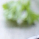 Envase de vidrio con paté de aceitunas negras sobre una tabla de madera y rodajas de pan