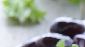 Envase de vidrio con paté de aceitunas negras sobre una tabla de madera y rodajas de pan