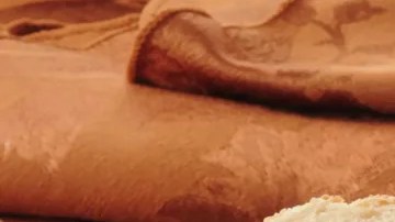 Tabla de madera con un frasco de vidrio con paté de pimientos de piquillo, untado en pedazos de pan