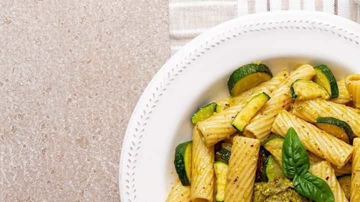 Plato blanco con rigatoni con calabacín y limón sobre una mesa