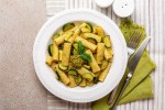 Plato blanco con rigatoni con calabacín y limón sobre una mesa