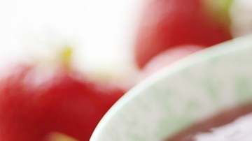 Porción de compota de frutos rojos en un recipiente blanco decorado con frutillas