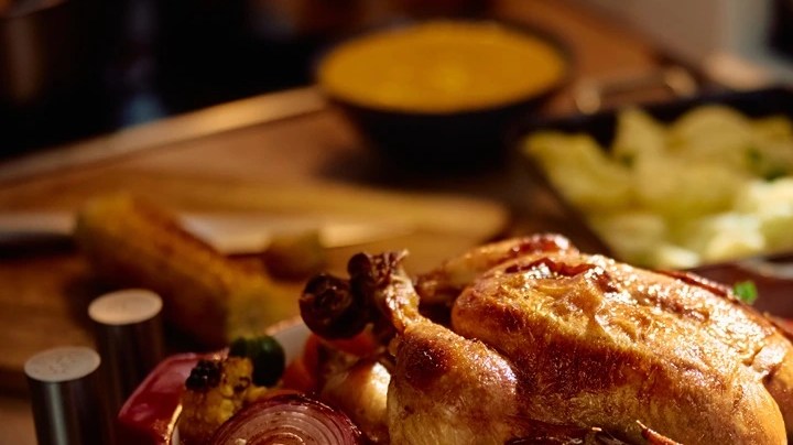 Pavo relleno sobre una bandeja de verduras y una mesa llena de comida para el meú semanal