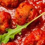 Plato azul con pasta pappardelle con salsa arrabbiata sobre una mesa de madera y manteles de cuadro