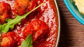 Plato azul con pasta pappardelle con salsa arrabbiata sobre una mesa de madera y manteles de cuadro