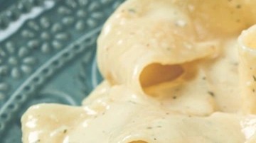 Pasta Pappardelle con salsa cremosa y parmesano sobre un plato verde y un tenedor