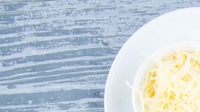 Pasta pappardelle con salsa de calabaza y tocino en un plato blanco sobre una mesa gris