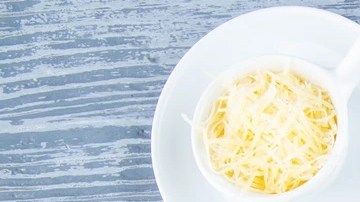 Pasta pappardelle con salsa de calabaza y tocino en un plato blanco sobre una mesa gris