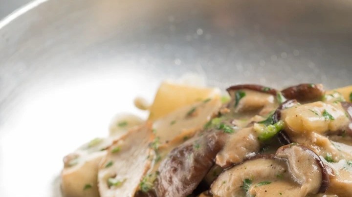 Pasta pappardelle con salsa de champiñones cremosa sobre un plato hondo plateado