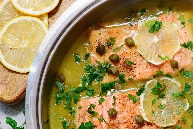 Olla de aluminio con picatta de salmón sobre una mesa de madera