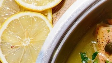 Olla de aluminio con picatta de salmón sobre una mesa de madera