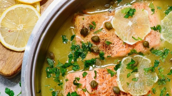 Olla de aluminio con picatta de salmón sobre una mesa de madera