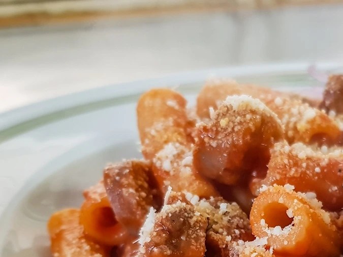 Plato blanco hondo con pasta rigatoni con chorizo y queso