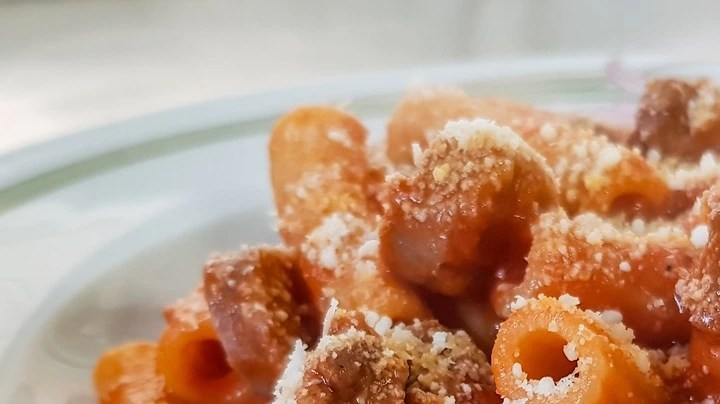 Plato blanco hondo con pasta rigatoni con chorizo y queso