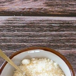 Plato gris con pasta rigatoni con crema y panceta, servido en una mesa junto a un vaso de agua y cubiertos