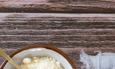 Plato gris con pasta rigatoni con crema y panceta, servido en una mesa junto a un vaso de agua y cubiertos