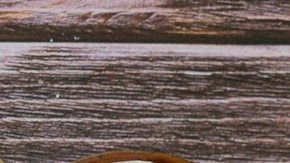 Plato gris con pasta rigatoni con crema y panceta, servido en una mesa junto a un vaso de agua y cubiertos