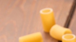 Rigatoni con espárragos en un plato negro sobre una mesa de madera