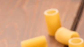 Rigatoni con espárragos en un plato negro sobre una mesa de madera