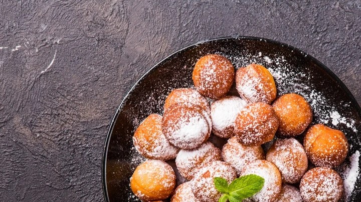 Plato negro con buñuelos de chocolate y azúcar glass