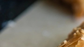 Empanada griega de queso picada por la mitad sobre una mesa de madera