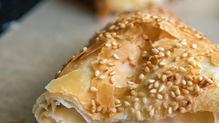 Empanada griega de queso picada por la mitad sobre una mesa de madera