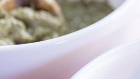 Salsa de mole amarillo servida en un tazón blanco con una cuchara de madera, sobre un mantel tradicional mexicano