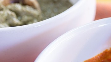 Salsa de mole amarillo servida en un tazón blanco con una cuchara de madera, sobre un mantel tradicional mexicano