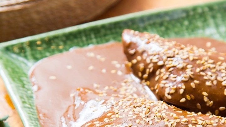 Rodajas de pechuga de pollo con mole manchamanteles en un plato cuadrado