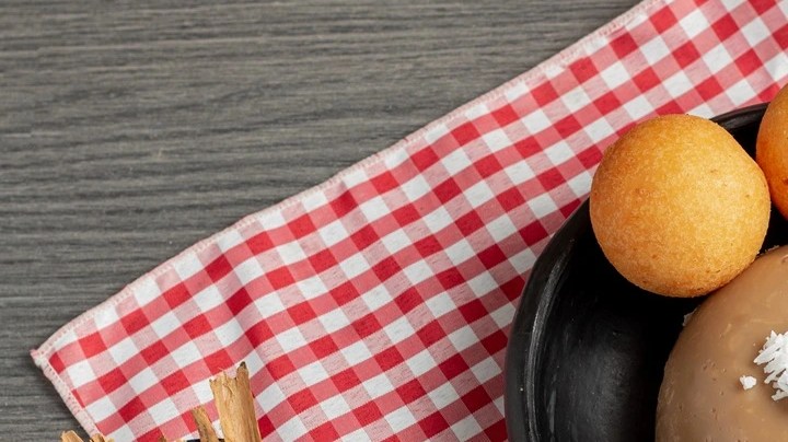 Buñuelos de nata sobre un plato negro y un mantel de cuadros rojo y blanco