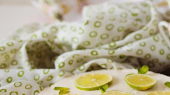 cheesecake de limón decorado con limones sobre una mesa de madera con un fondo blanco